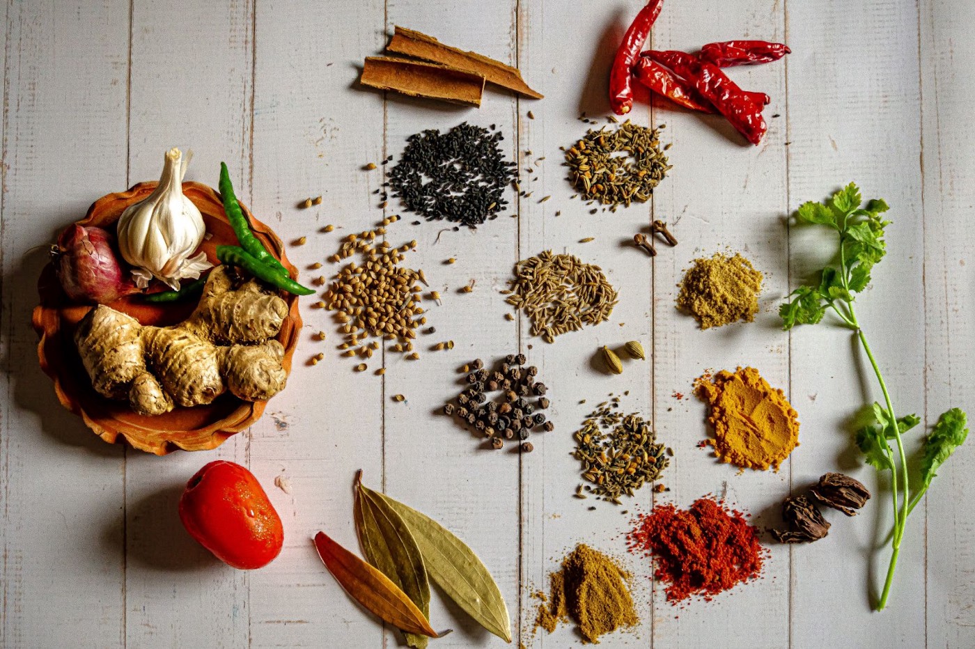 Multiple different spices on a white wooden table.