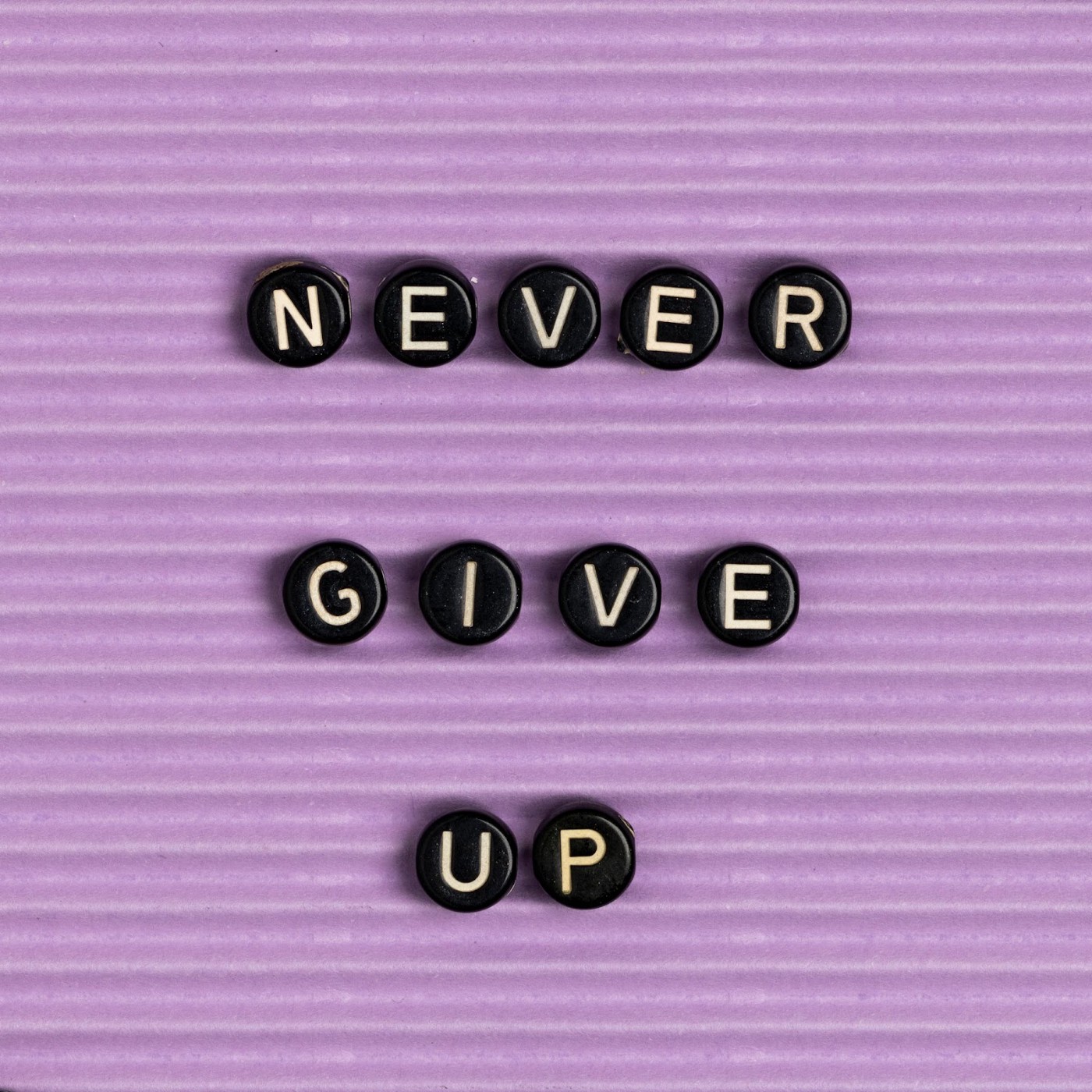 “NEVER GIVE UP” written on black beads.
